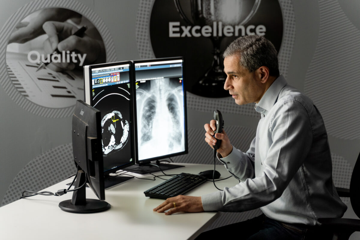 Doctor at his desk examining chest x-rays on his monitors