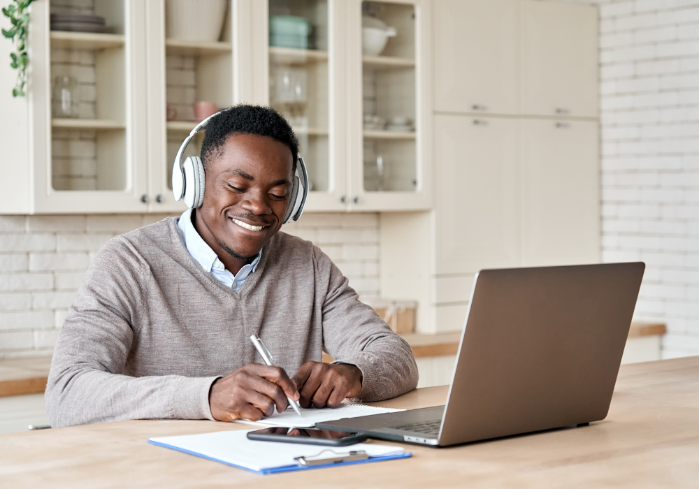 A man wearing headphones on his laptop smiling whilst eLearning